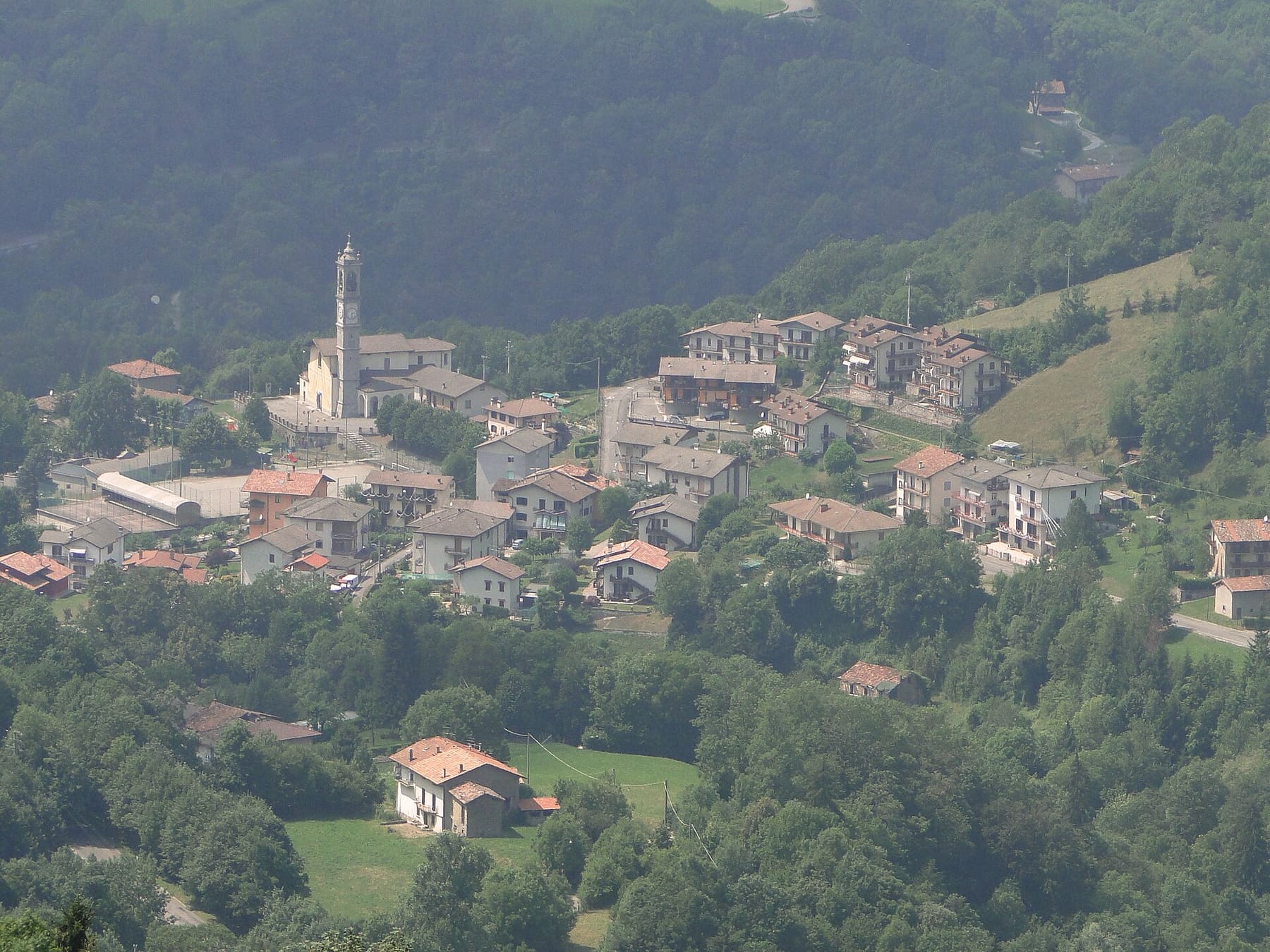 Rigosa, frazione di Algua in Val Serina, vista dall'alto: il campanile e le case tra prati e boschi