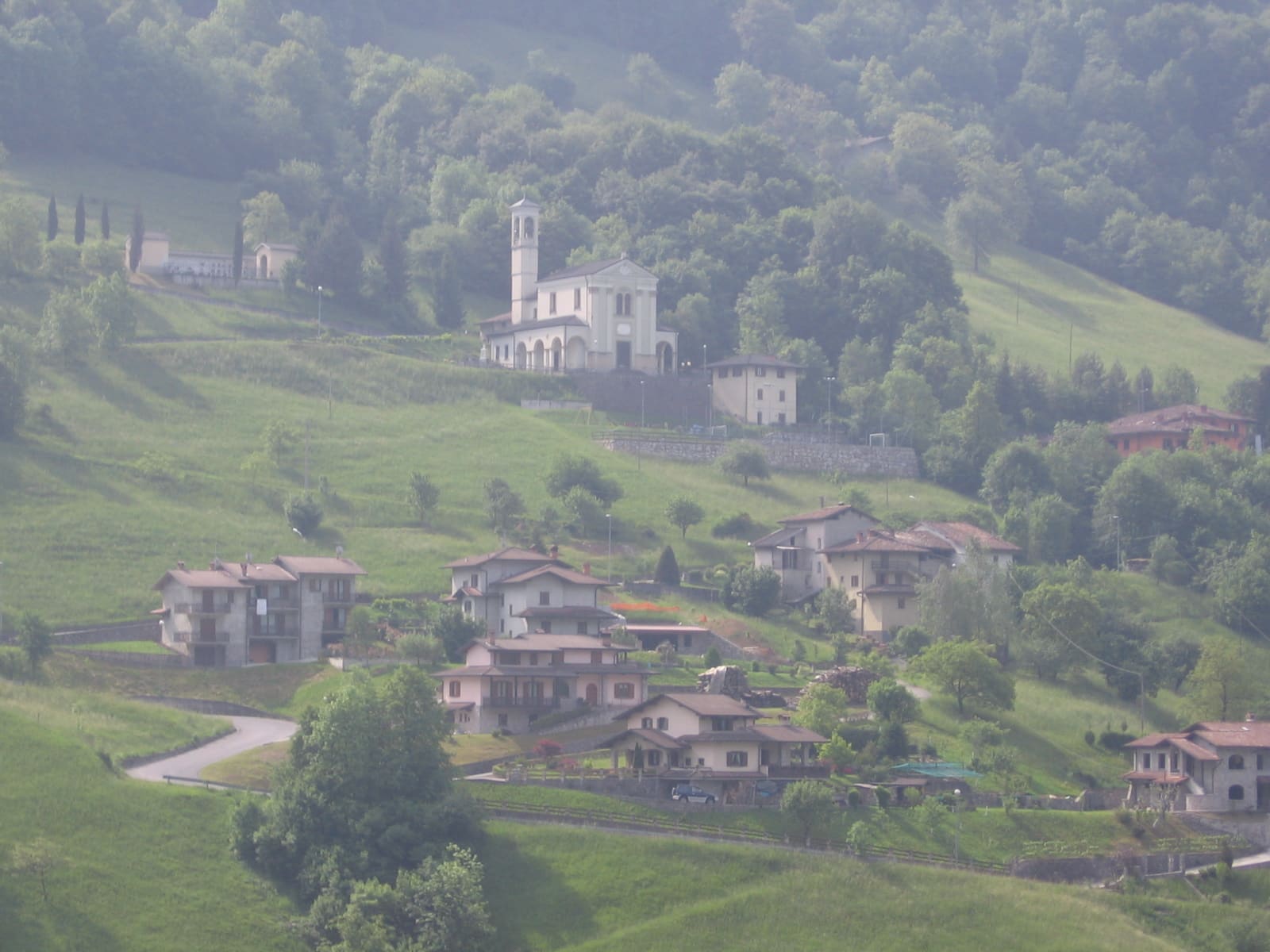 Cornalta, frazione di Bracca, con la chiesa di San Bartolomeo e le case sparse sui prati sopra la Val Serina