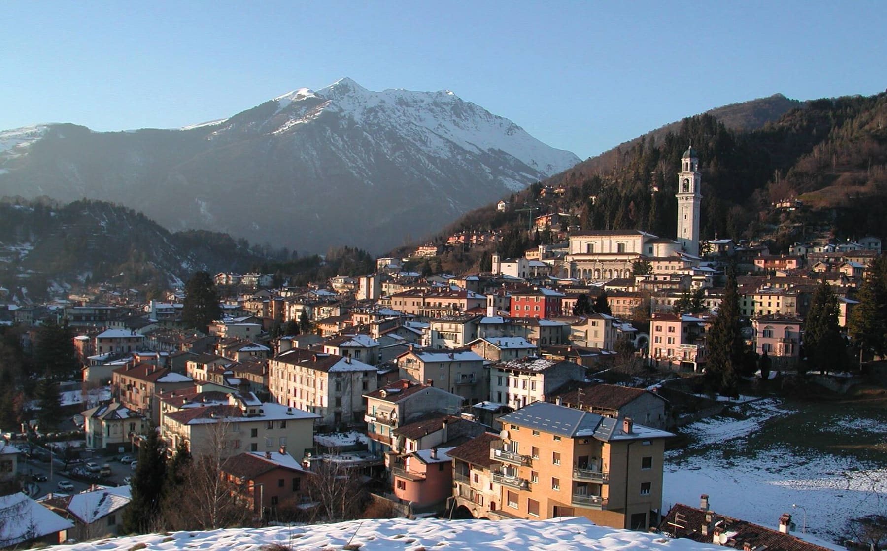 Clusone innevato con il campanile della basilica di Santa Maria Assunta e le montagne dell'alta Valle Seriana sullo sfondo