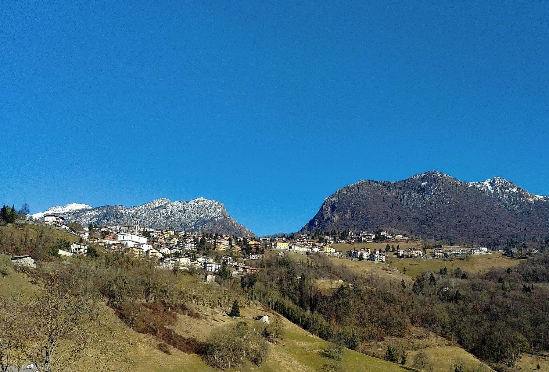 Costa Serina sul versante soleggiato, con le cime innevate del Suchello e dell'Alben sullo sfondo