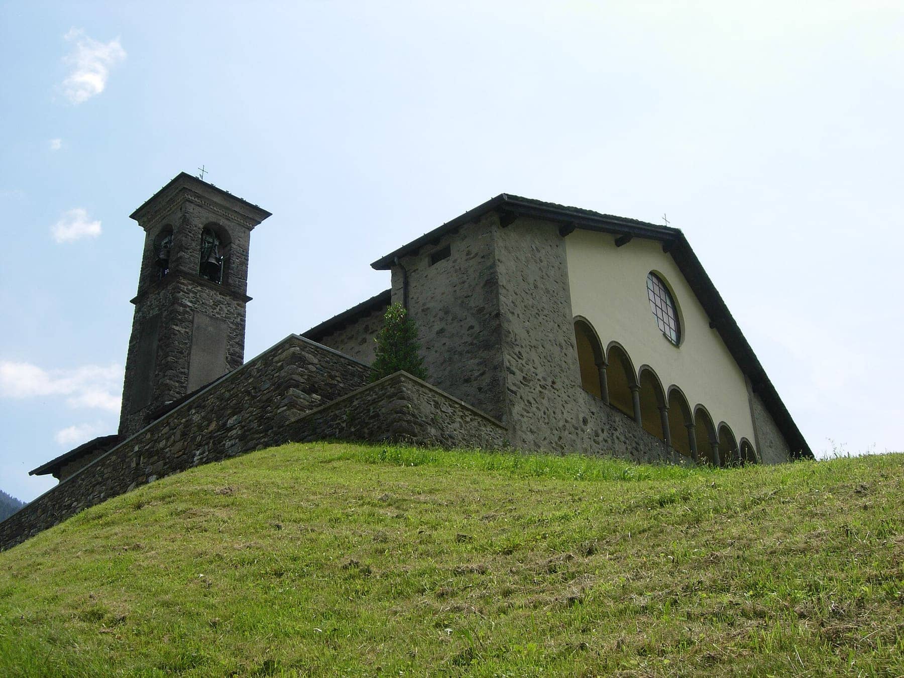 La chiesa di Santa Maria Nascente a Gromo San Marino, frazione di Gandellino, con portico e campanile in pietra sul prato