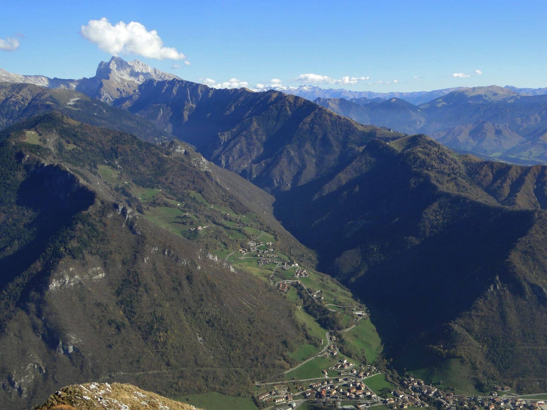 La Valzurio vista dall'alto in autunno, con i prati e le frazioni di Oltressenda Alta sul versante e le cime rocciose delle Orobie sullo sfondo