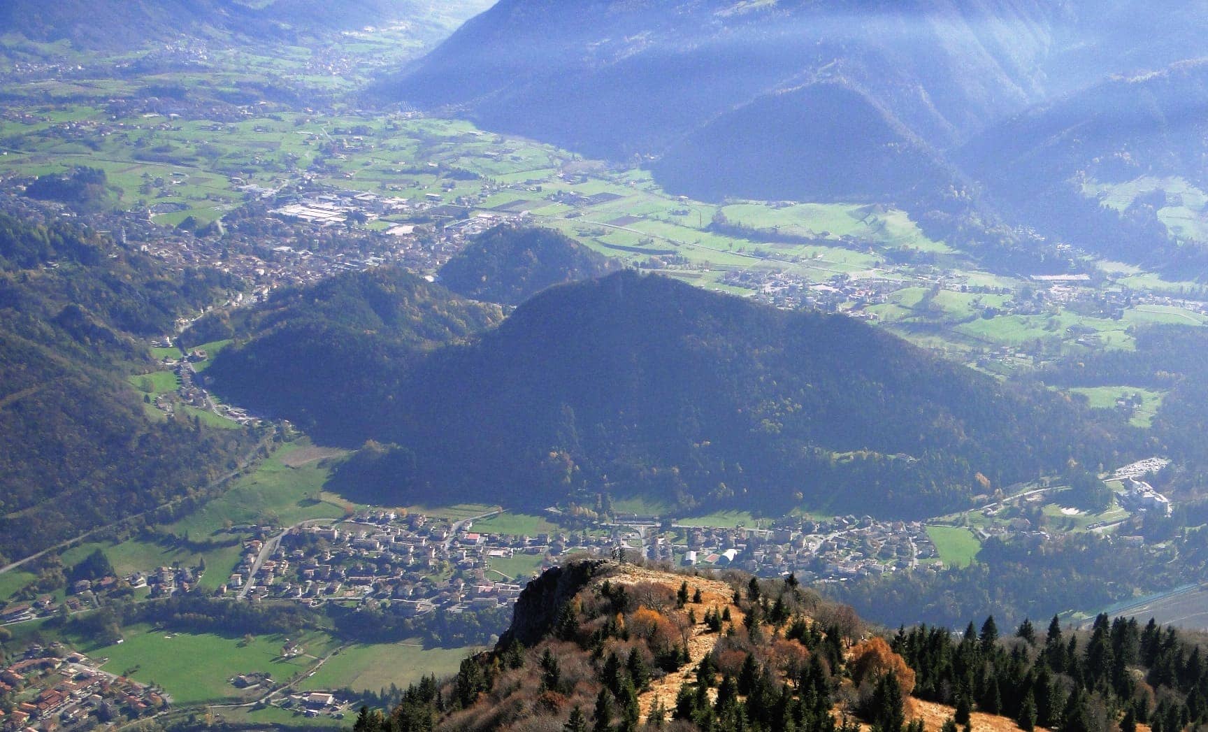 Piario e la piana di Clusone in Alta Valle Seriana visti dall'alto, con i prati e le montagne in controluce