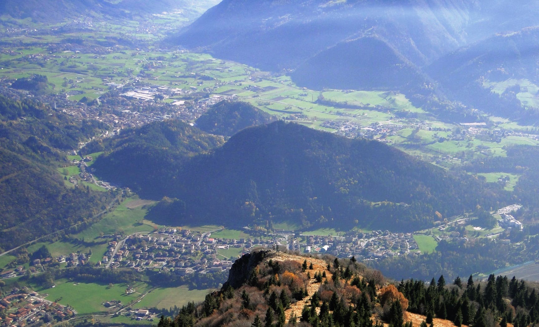 Piario e la piana di Clusone in Alta Valle Seriana visti dall'alto, con i prati e le montagne in controluce