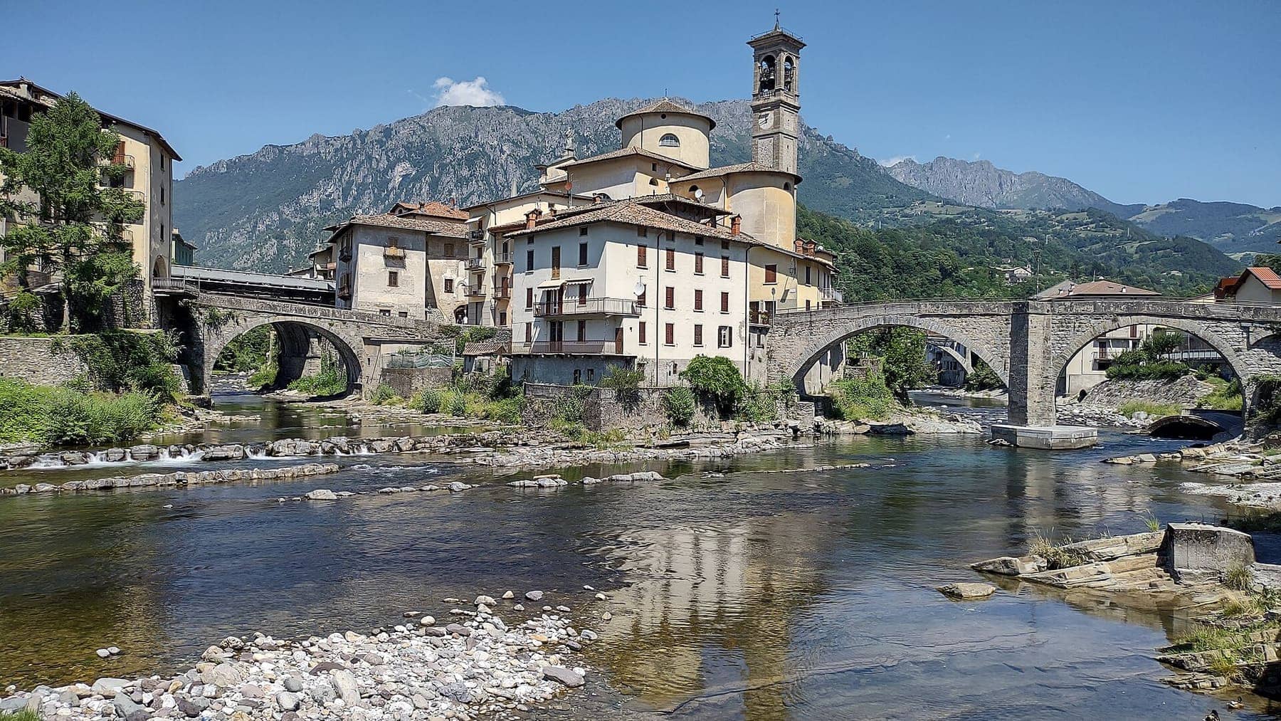 San Giovanni Bianco con i ponti in pietra ad arco sul Brembo, la chiesa parrocchiale col campanile e le Prealpi sullo sfondo