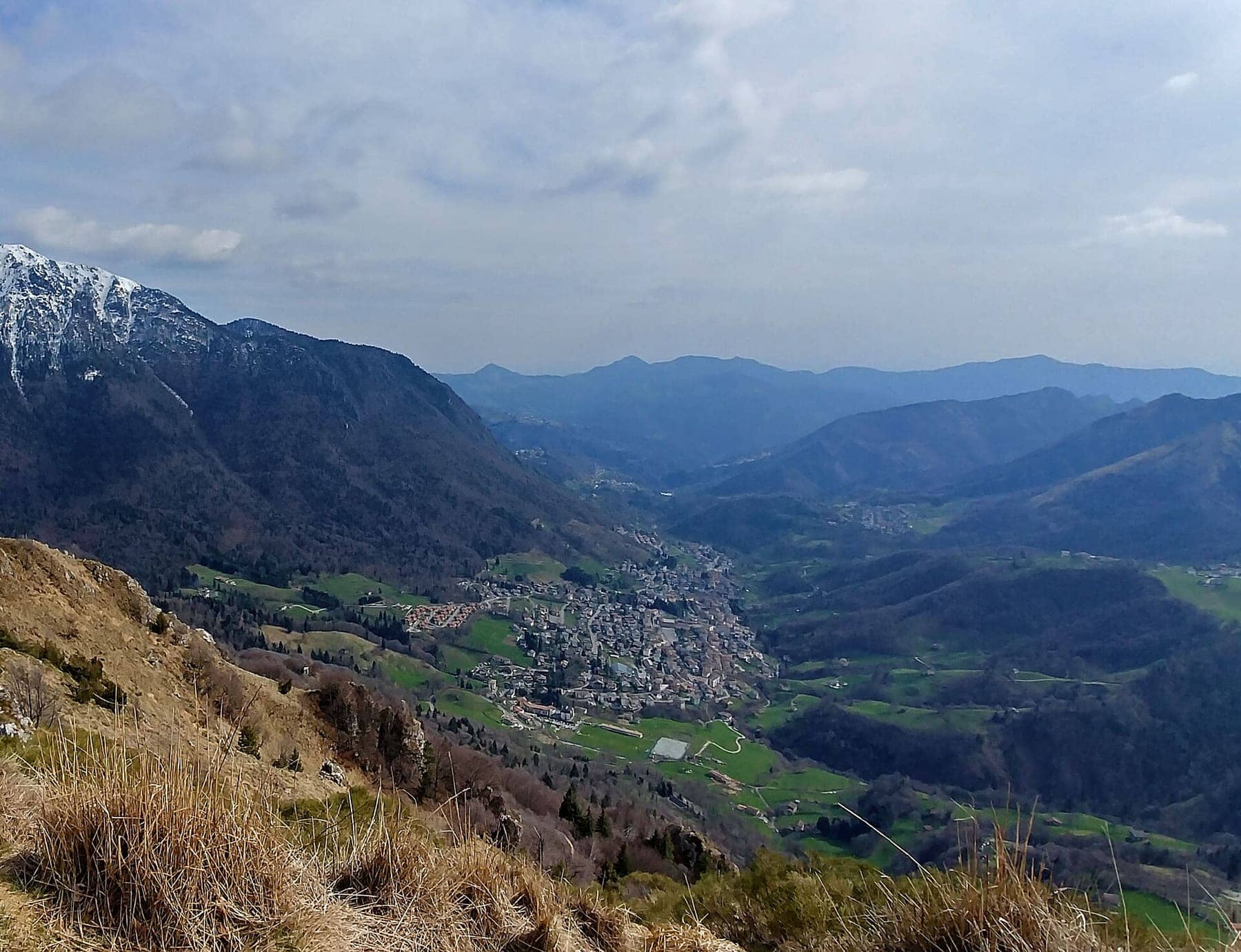 La Val Serina in primavera dal monte Castello, con il paese di Serina nel fondovalle e le cime ancora innevate