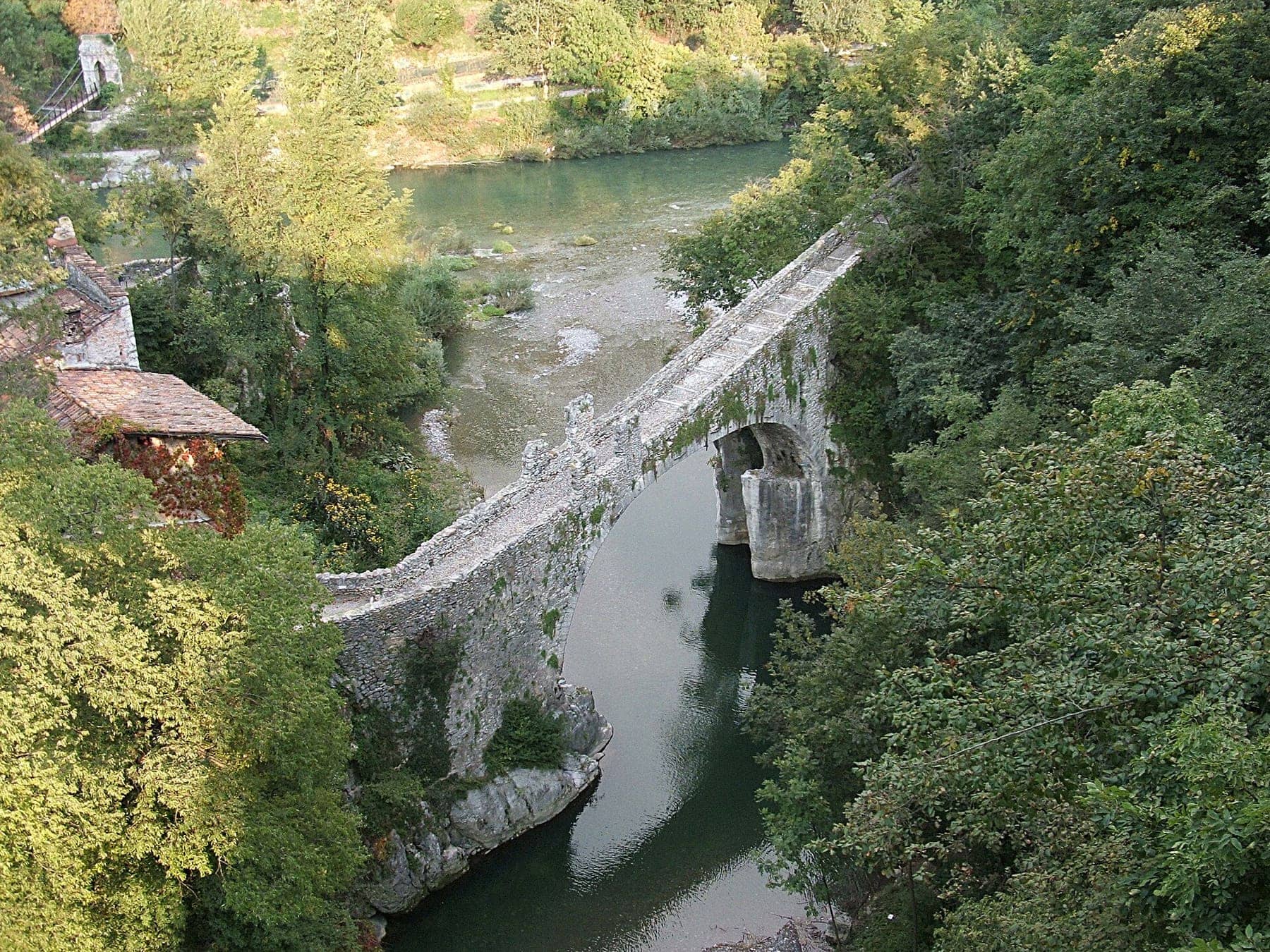 Il ponte di Attone, arco medievale in pietra sul torrente Imagna a Clanezzo, con la passerella sospesa sul Brembo sullo sfondo