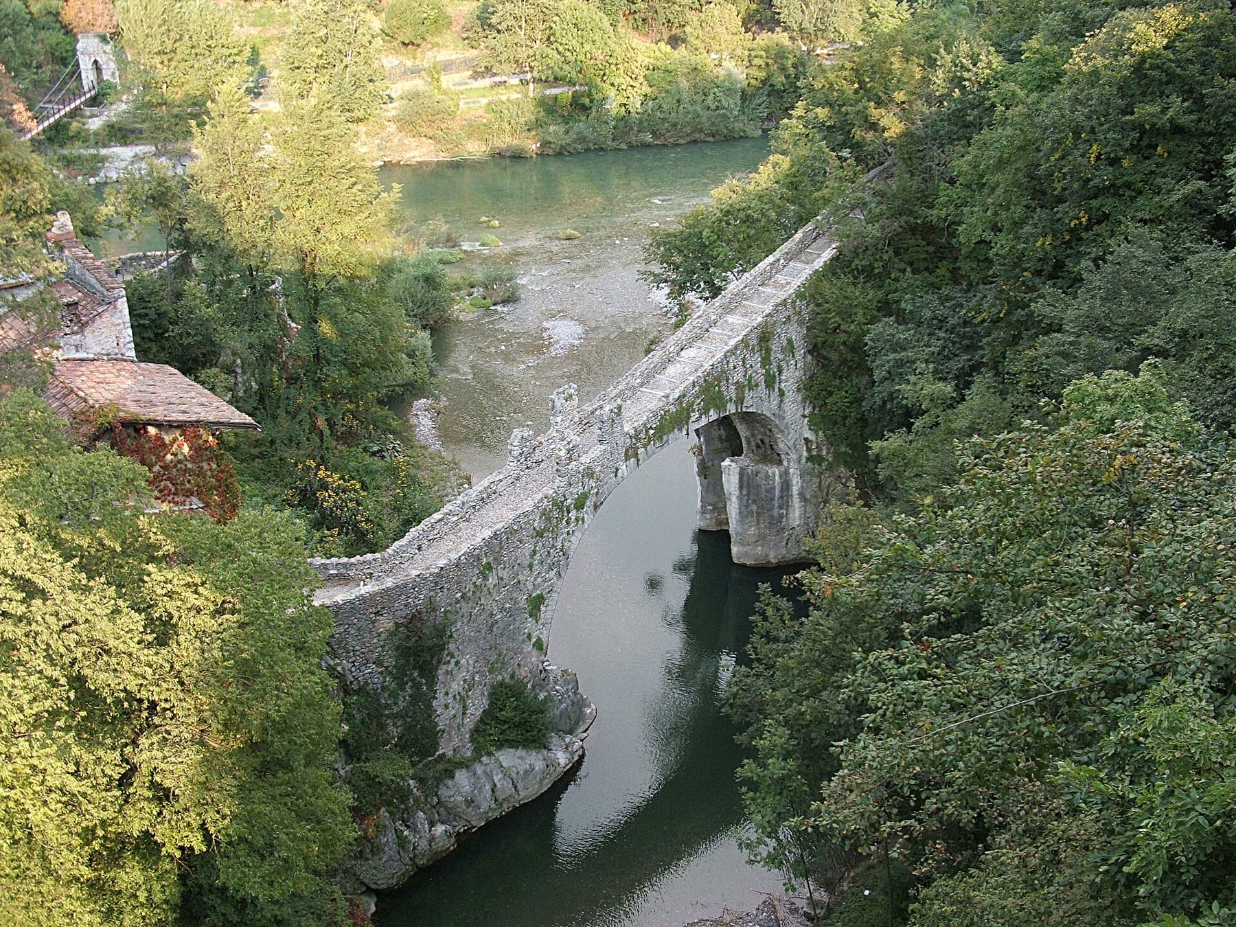 Il ponte di Attone, arco medievale in pietra sul torrente Imagna a Clanezzo, con la passerella sospesa sul Brembo sullo sfondo