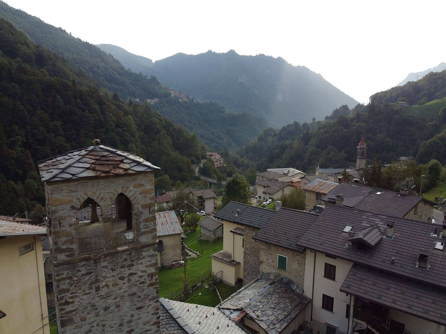 La torre medievale della frazione Torre di Valtorta con i tetti in pietra del paese e la valle boscosa sullo sfondo