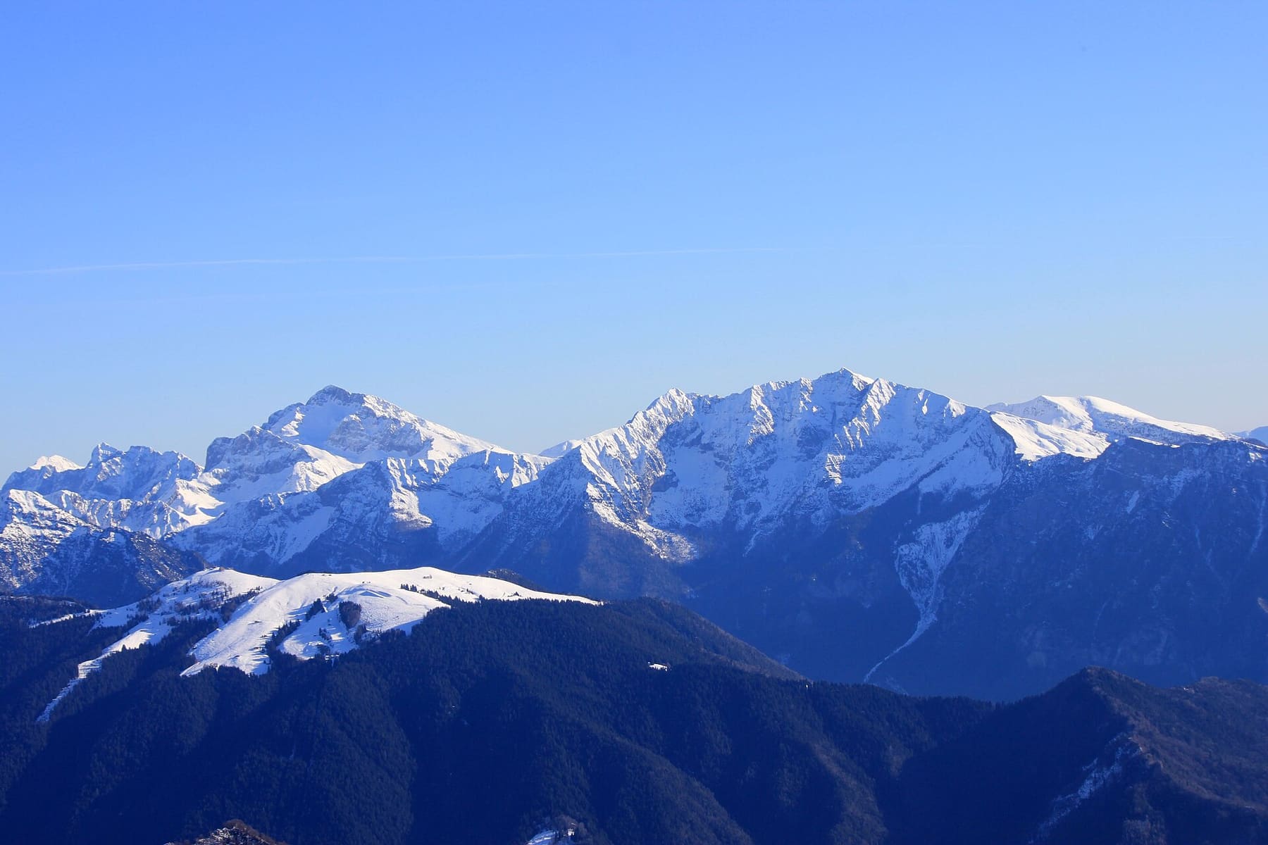 Il dosso innevato del Monte Torcola, la montagna delle piste di Piazzatorre, con la cresta del Pizzo Arera sullo sfondo in inverno