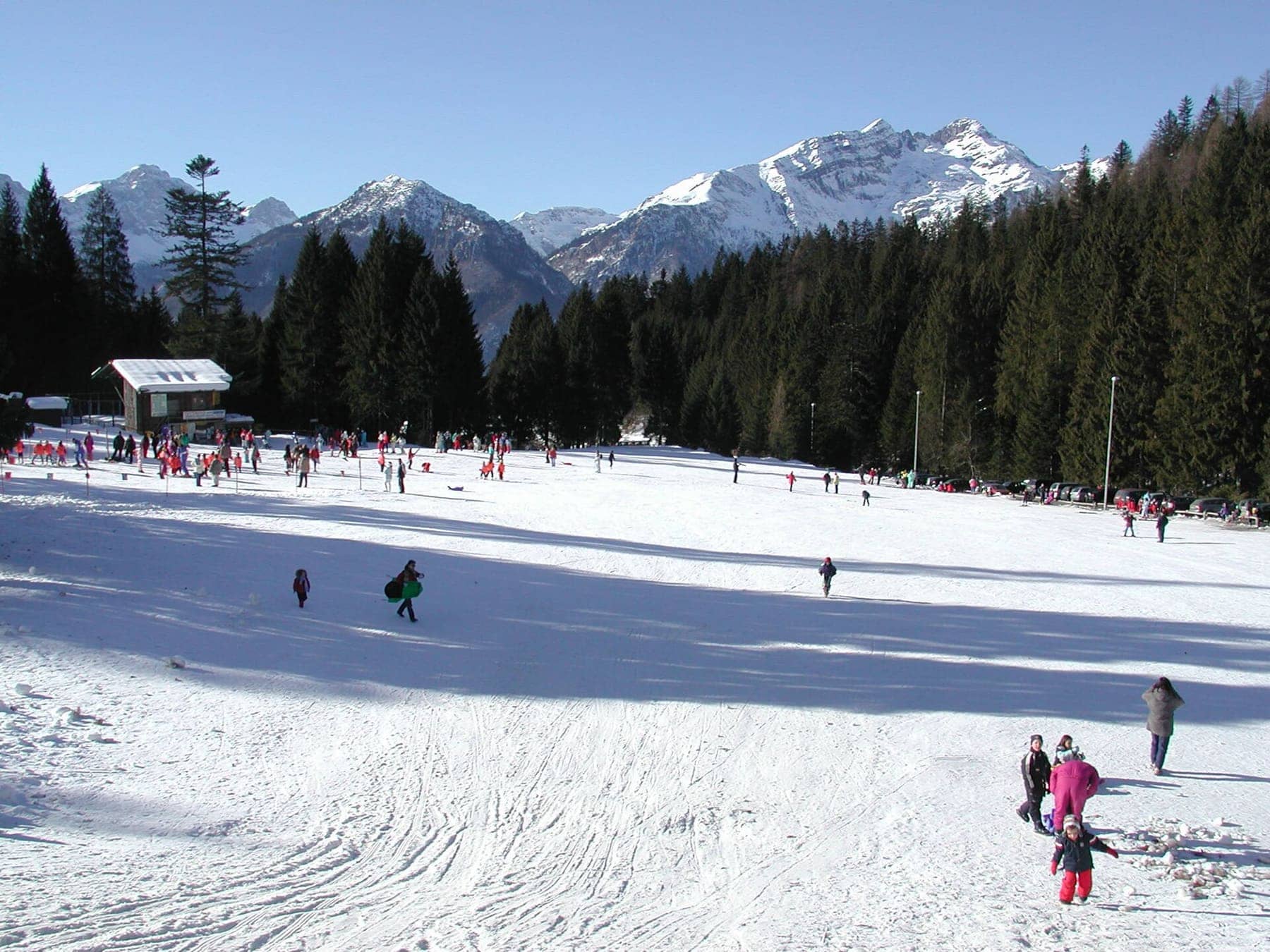 Il campo scuola innevato di Spiazzi di Gromo con la baita, gli abeti e le cime delle Orobie sullo sfondo