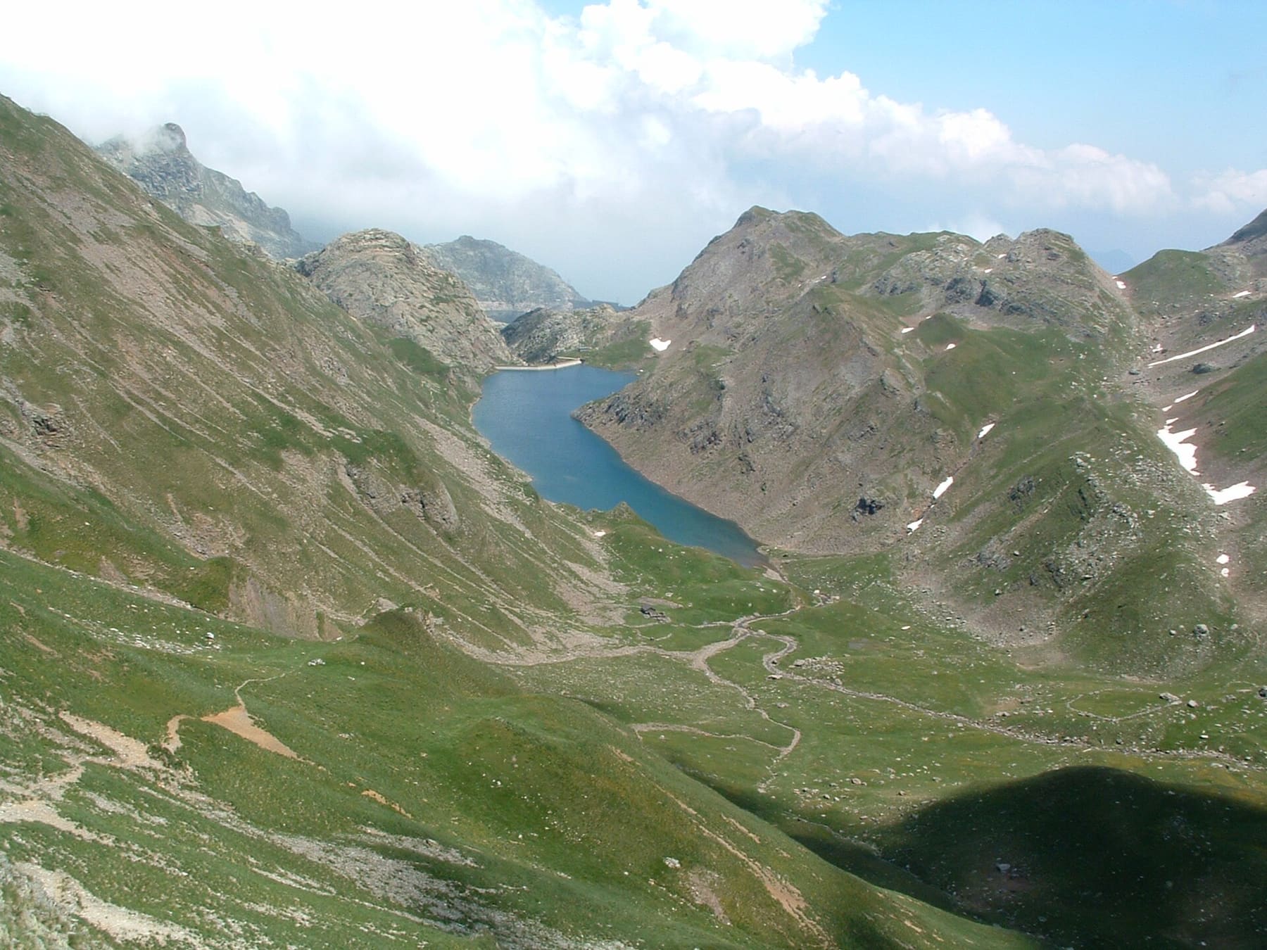Il lago d'Aviasco sopra Valgoglio visto dall'alto, con la diga e le creste erbose delle Orobie in estate