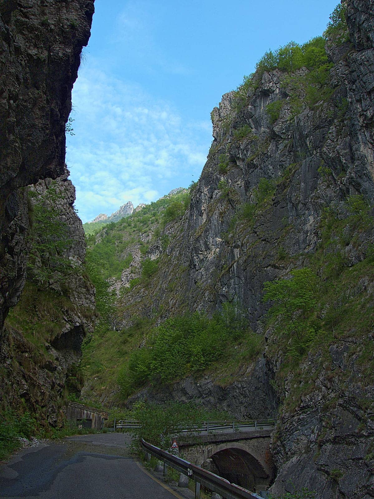 La strada dell'Orrido della Val Taleggio stretta tra alte pareti di roccia, con un ponte sul torrente Enna