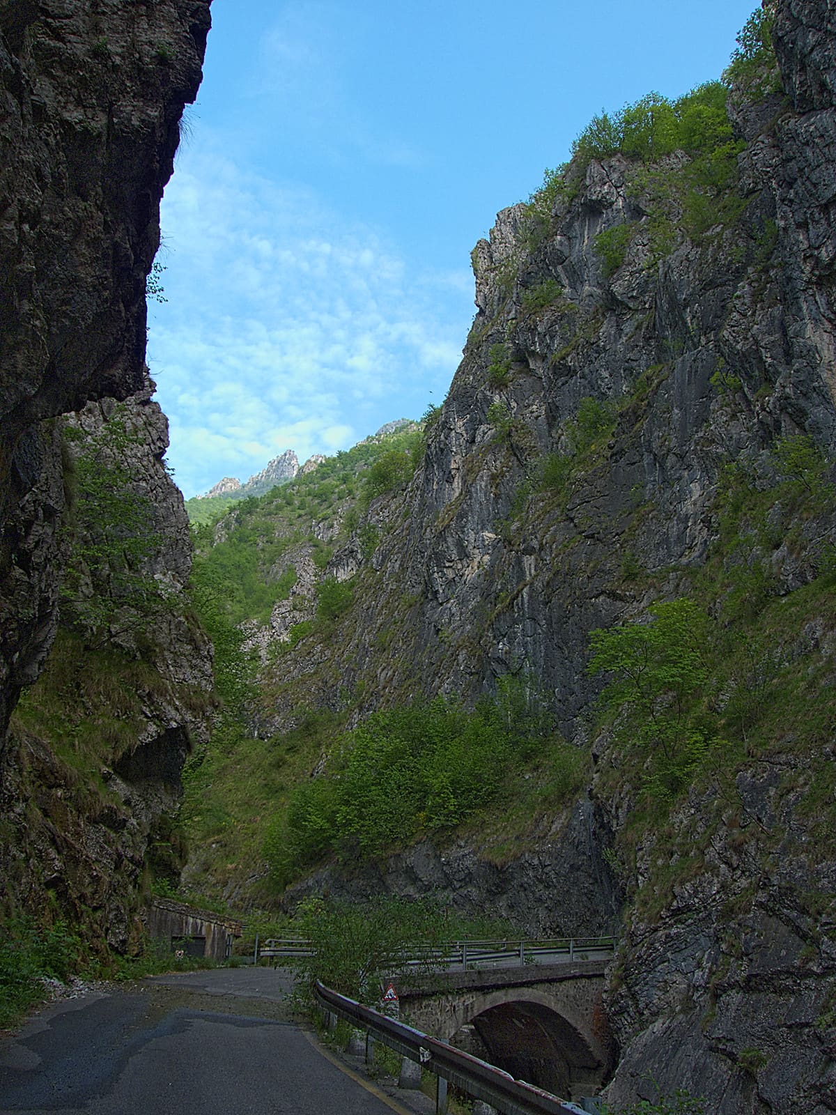 La strada dell'Orrido della Val Taleggio stretta tra alte pareti di roccia, con un ponte sul torrente Enna