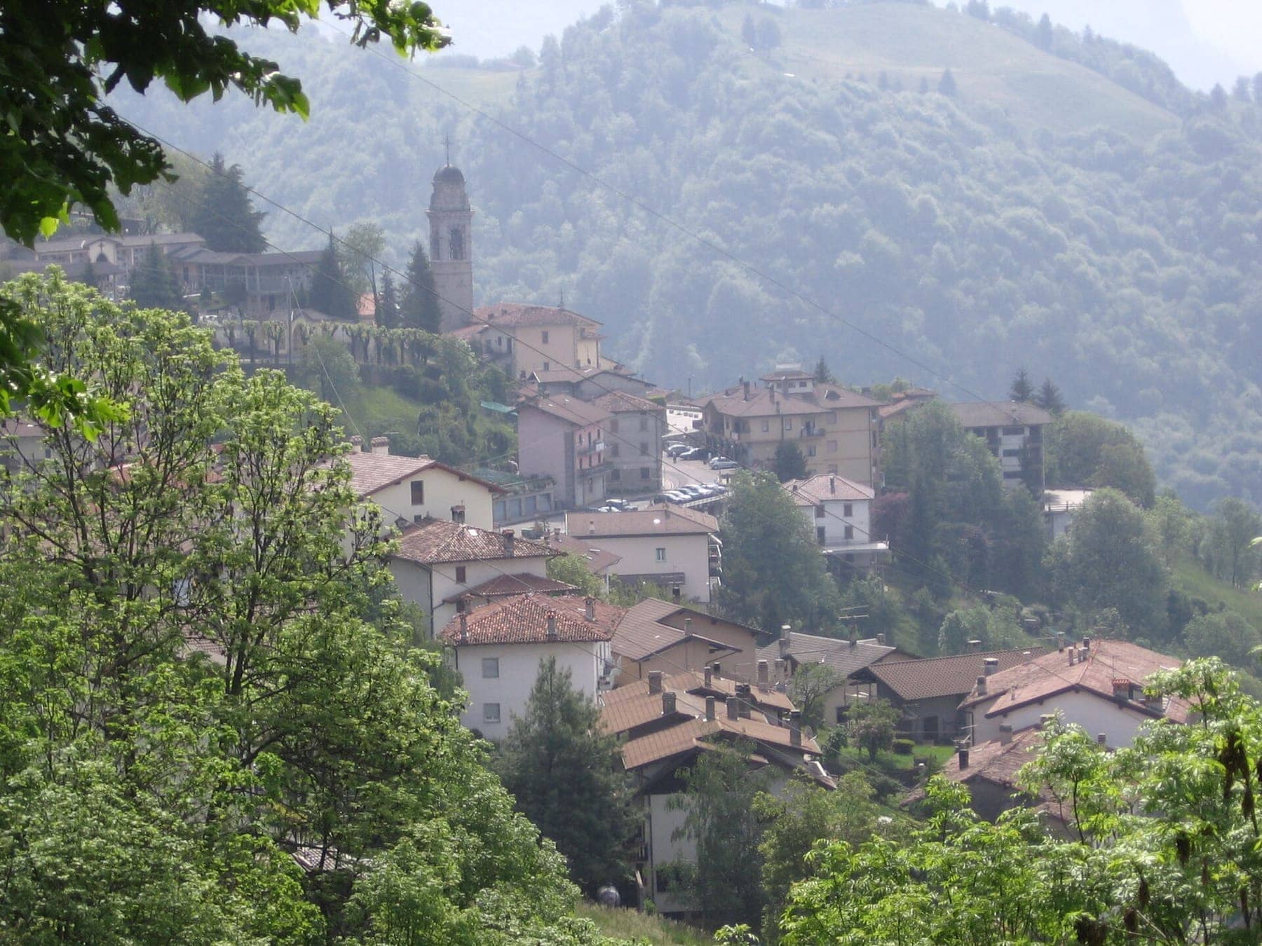 Il paese di Dossena, sede del Ponte nel Sole, con il campanile della parrocchiale tra i tetti e i boschi
