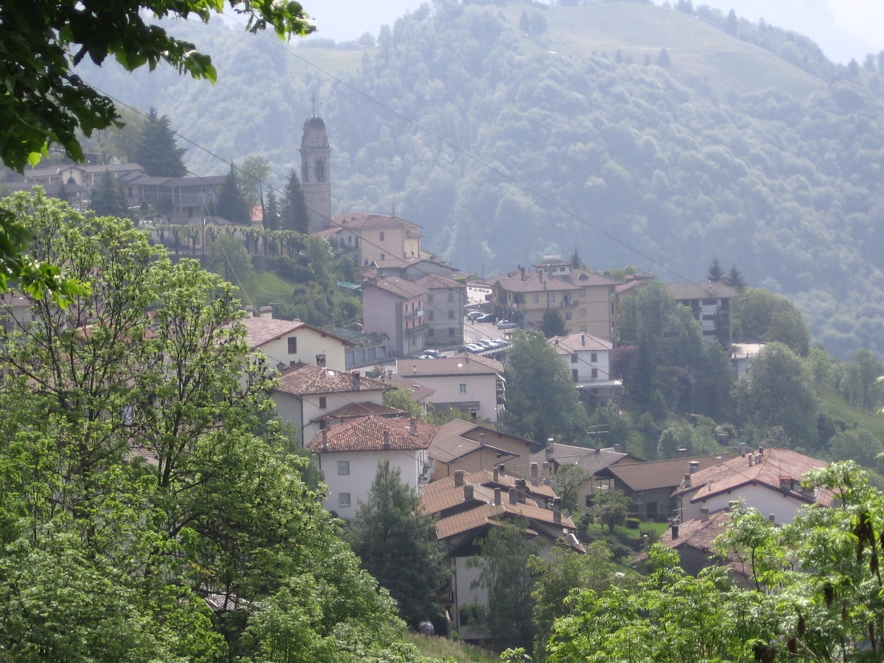 Il paese di Dossena, sede del Ponte nel Sole, con il campanile della parrocchiale tra i tetti e i boschi