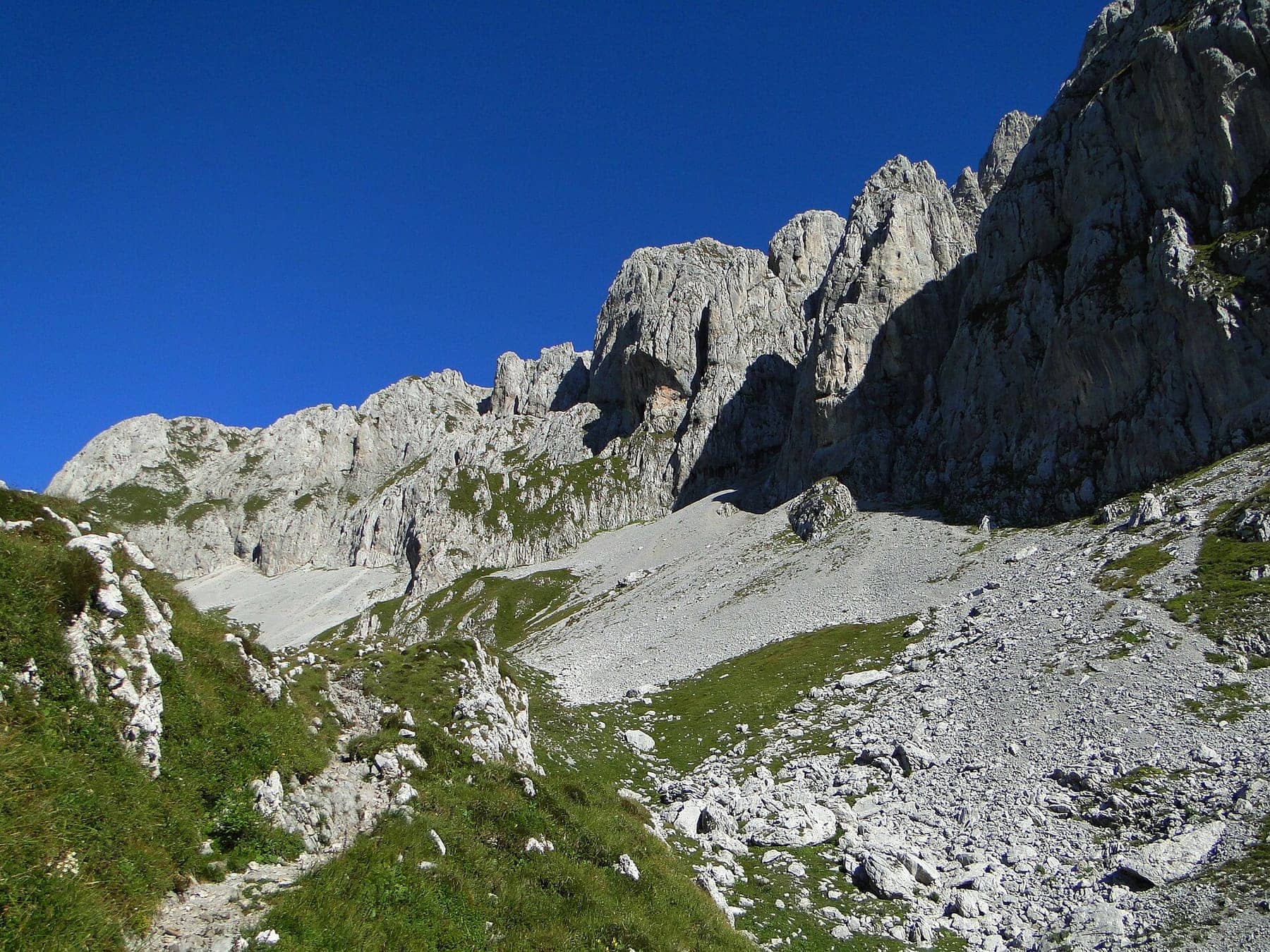 La parete sud della Presolana con i ghiaioni ai piedi delle rocce, nei pressi della Grotta dei Pagani, sotto un cielo terso
