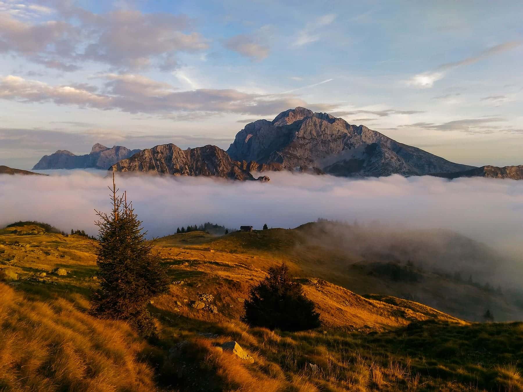 Il pizzo Arera emerge da un mare di nuvole al tramonto, visto dai pressi dei Tre Pizzi in Val Brembana